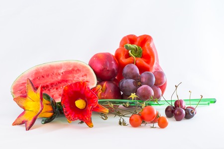 Group of red fruits and vegetables with glass flower, isolated on white .の写真素材