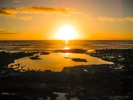 Playa de Las Americas. Colorful sunset reflecting on the water of the ocean and the rocks. Tenerife, Canary, Spain.の写真素材