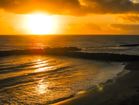Playa de Las Americas. Colorful sunset reflecting on the water of the ocean and the rocks. Tenerife, Canary, Spain.の写真素材