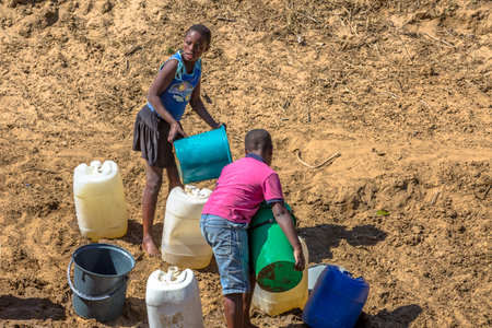 African children collecting water from the river with tanks and buchets, on the road leading to UMkhuze Game Reserve, South Africa.のeditorial素材