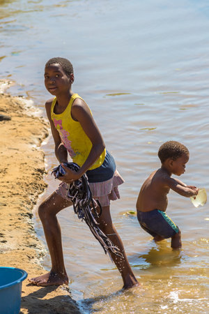 African children washing their clothes to the river on the road leading to UMkhuze Game Reserve, South Africa.のeditorial素材