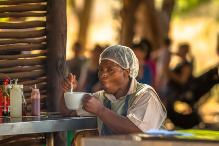 Blyde River Canyon Nature Reserve, South Africa - August 19, 2014:  African cook sitting eating soup during a breakのeditorial素材