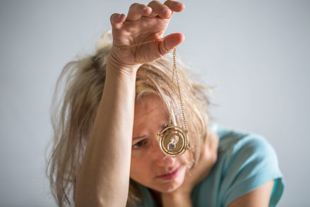 Portrait of a blond woman holding an hourglass and contemplating time. Concept of time passing,...