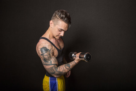 Bologna, Italy - June 21, 2014: Half body portrait of a bare chested bodybuiler man flexing his muscles and showing artistic tatoo during a private exhibition in the city gymのeditorial素材
