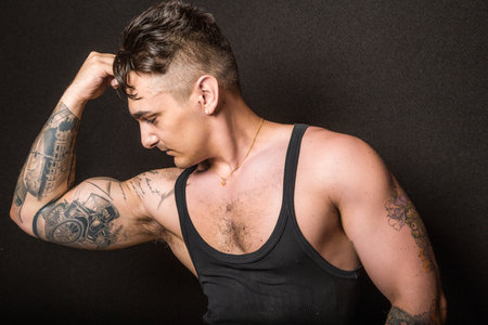 Bologna, Italy - June 21, 2014: Half body portrait of a bare chested bodybuiler man flexing his muscles and showing artistic tatoo during a private exhibition in the city gymのeditorial素材