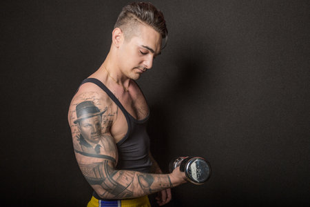 Bologna, Italy - June 21, 2014: Half body portrait of a bare chested bodybuiler man flexing his muscles and showing artistic tatoo during a private exhibition in the city gymのeditorial素材