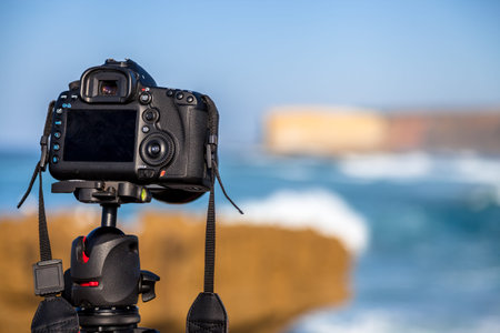 Closeup of a camera on a tripod outdoors. Camera is Canon. background Landscape out of focus....