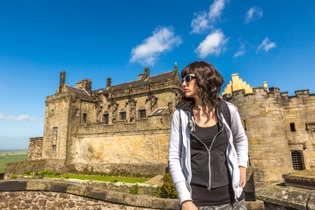 Young tourist woman standing in front of the famous Stirling Castle, in Stirling town, Central Scotland, UK, Europe on a sunny day.の写真素材