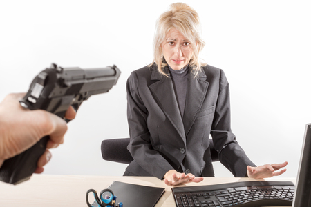 Employee on the menace of a gun during a bank robbery, white background, isolated.の写真素材