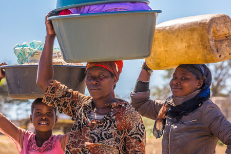 UMkhuze Game Reserve, South Africa - August 24, 2014: African women go to wash their clothes in the river, carrying basins on their headsのeditorial素材