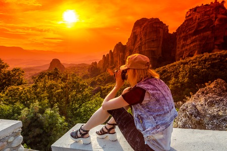 A travel photographer takes pictures of the spectacular monasteries of Meteora at sunset. Meteora is an area of Central Greece with several monasteries built on top of natural sandstone rock pillars.の写真素材