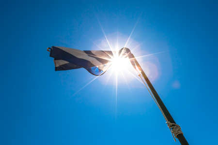 Greek national flag waving on the blue sky background in a sunny day.の写真素材