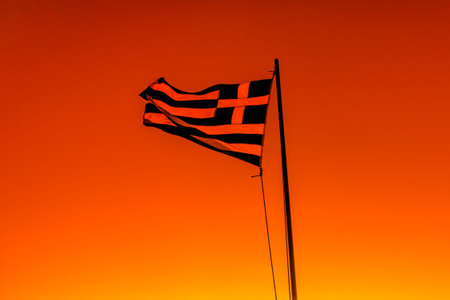 Greek national flag silhouette waving in  black backlight on sky background at sunset.