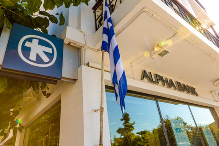Olimpia town, Peloponnese, Greece - August 19, 2015:  Greek bank window with ATM and flag of Greece of the local Alpha Bankのeditorial素材