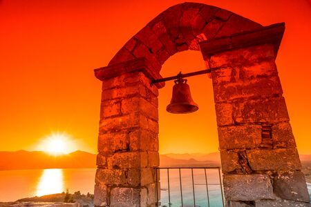 Bell in a dramatic sunset sky in Palamidi  which dominates Nafplio city, Peloponnese, Greece.の写真素材
