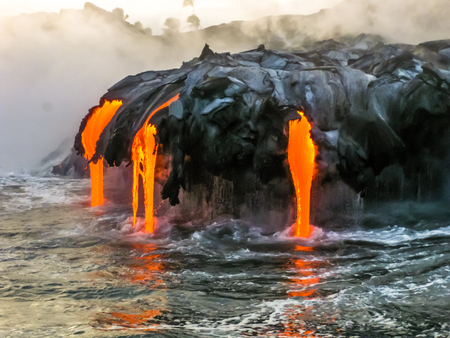 Sea view of Kilauea Volcano in Big Island, Hawaii, United States. A restless volcano that has been in business since 1983. Shot taken at sunset when the lava glows in the dark as jumps into the sea.