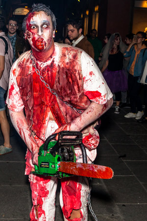 Bologna, Italy - May 21, 2016: Bologna zombie apocalypse walk. Halloween costume maniac with bloody clothes and chainsaw and scares people.のeditorial素材