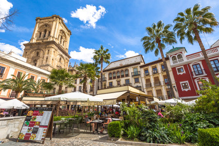 Granada, Andalucia, Spain - April 16, 2016: tourists eat at restaurant El Deseo in Plaza de las Romanillas. On background the Tower of Granada Cathedral in a sunny day.のeditorial素材
