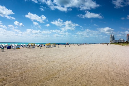 Beach umbrellas, deck chairs and people sunbathing in the South Beach neighborhood of Miami Beach in Florida. South Beach is famous for its tropical sea, the long white beaches and nightlife.の写真素材