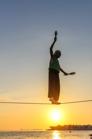 Key West, Florida, United States - April 13, 2012: a tightrope walker tosses of skittles. Show of street artists that takes place every day during the sunset celebration at Mallory Square in Key West.のeditorial素材
