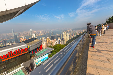 Hong Kong, China - December 7, 2016: The Peak Tower and rooftop restaurant atop Victoria Peak in a sunny day view from observation deck of Peak Galleria. Tourists observe the Victoria Harbour skyline.のeditorial素材