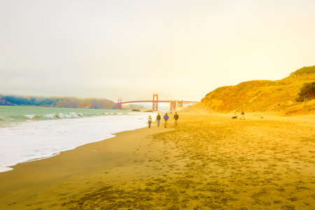 San Francisco, California, United States - August 17, 2016: spectacular view of Golden Gate Bridge from Baker Beach at sunset. Tourists walk on popular Baker Beach.Holidays, travel and leisure conceptのeditorial素材