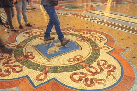 MILAN, ITALY- MARCH 7, 2017: Tourists stepping on the Bulls Balls of mosaic in Milano inside Galleria Vittorio Emanuele II gallery in Duomo square. This tradition practice may bring good luck.のeditorial素材