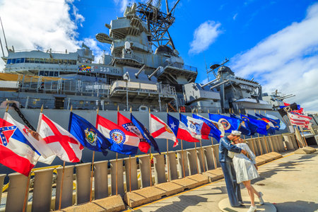 HONOLULU, OAHU, HAWAII, USA - AUGUST 21, 2016: Sailor and nurse in NY Times Square 1945 victory kiss statue at Missouri Memorial with flags at Pearl Harbor base.のeditorial素材