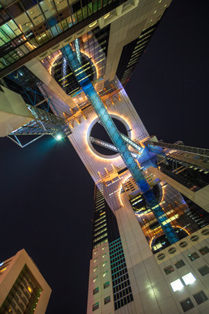 Osaka, Japan - April 28, 2017: bottom view of Lumi Sky Walk, the panoramic corridor joining the two towers of Floating Garden Observatory in Umeda Sky Building by night. Osaka, Japan - April 28, 2017: bottom view of Lumi Sky Walk, the panoramic corridor joining the two towers of Floating Garden Observatory in Umeda Sky Building by night.