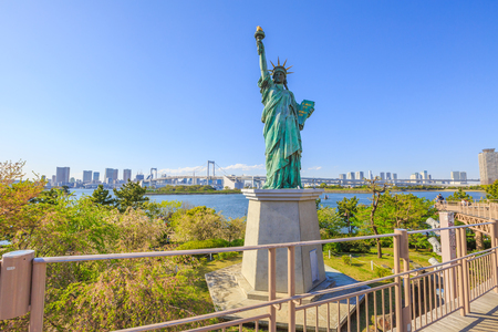 Urban landscape of Statue of Liberty and Rainbow Bridge, icons of Odaiba Island in Tokyo, Japan. Replica of famous Statue of Liberty of New York. Tokyo skyline and skyscrapers on background.の写真素材