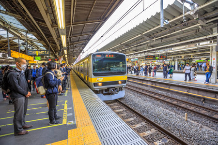 Tokyo, Japan - April 17, 2017: people waiting on tracks of Chuo Line local, for Akihabara, the yellow line of JR Line, a rail service that crosses east-west Tokyo downtown. Shinjuku Station.のeditorial素材