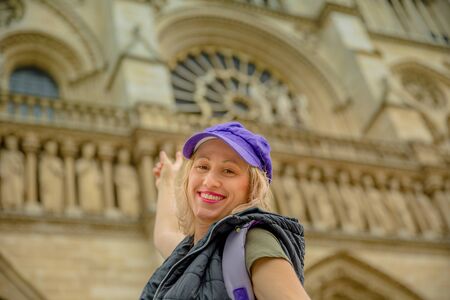 Happy young tourist caucasian woman pointing Notre Dame Cathedral on blurred backgroundの写真素材