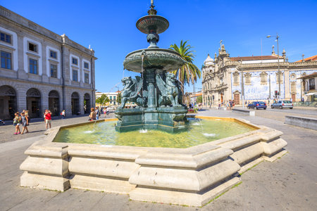 Porto, Portugal - August 11, 2017: Fountain of Lions, 19th century fountain, in Parade Leitao Square and Carmo church famous for azulejos on background. Historical city of Oporto.のeditorial素材