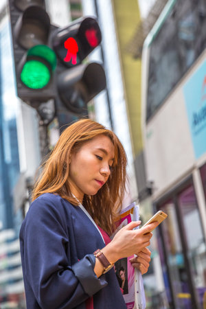 Hong Kong, China - December 6, 2016: A busy woman at the traffic signal of Yee Wo street junction, located at Causeway Bay on the Hennessy Road. This busy junction is famous for fashion and luxury.のeditorial素材