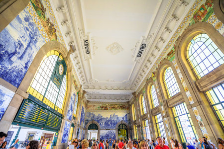 Porto, Portugal - August 13, 2017: tourists visit historic train station of Oporto. Azulejos, painted ceramic tileworks on the walls of main hall of Sao Bento Railway Station, a Heritage Site.のeditorial素材