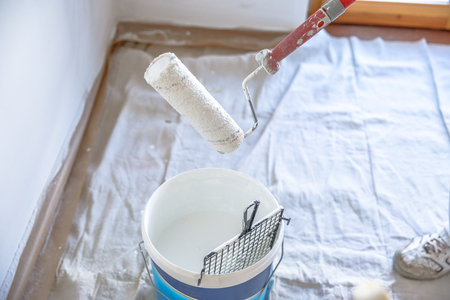 Close up of draining paint roller in bucket in renovation room with whitewasherの写真素材
