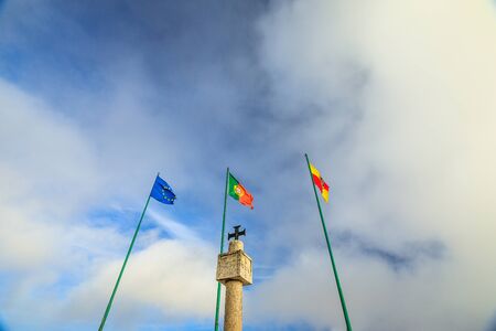 Flags of European Union, Portuguese flag and Nazare Flag waving in the blue sky. Miradouro do Suberco in Nazare Sitio, Central Portugal, Atlantic coast.の写真素材