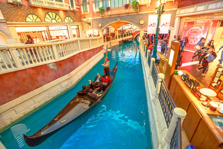 Macau, China - December 9, 2016: gondolier sings famous italian songs to tourists during a romantic ride in an authentic gondola down Grand Canals of Shoppes at the Venetian Luxury Hotel and Casino.のeditorial素材