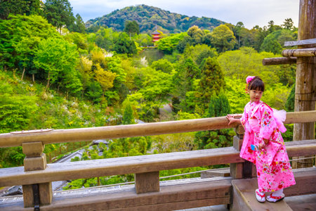 Kyoto, Japan - April 24, 2017: a child dressed with japanese kimono posing for photo.Pagoda of Kiyomizu Temple, one of the most celebrated temples of Japan and popular landmark in Kyoto, on backgroundのeditorial素材