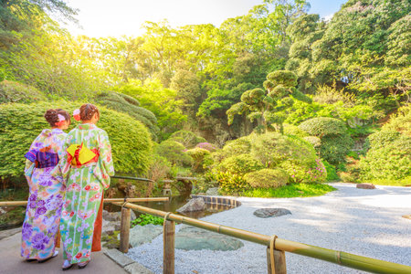 Kamakura, Japan - April 23, 2017: two women wearing in traditional japanese kimono looking japanese zen garden inside Take-dera Temple in Kamakura. Sunset light. Meditative and buddhism conceptのeditorial素材