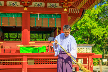 Kamakura, Japan - April 23, 2017: close-up of Shinto priest who cleans inside Tsurugaoka Hachiman Shinto shrine in the city of Kamakura, Kanagawa Prefecture.のeditorial素材