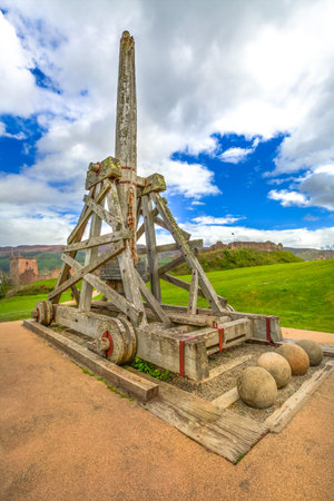 Trebuchet catapult in a cloudy sky in the yard of the Urquhart Castle in Scotland United Kingdom.