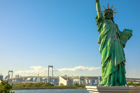 Close up of Statue of Liberty and Rainbow Bridge, icons of Odaiba Island in Tokyo, Japan. Replica of famous Statue of Liberty of New York. Tokyo skyline and skyscrapers on background.の写真素材