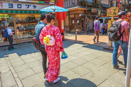 Tokyo, Japan - April 19, 2017: woman wearing kimono with parasol, the national tradition costume of Japan, walking on Nakamise-dori, a market street in Senso-ji Temple in Asakusa, a popular landmark.のeditorial素材