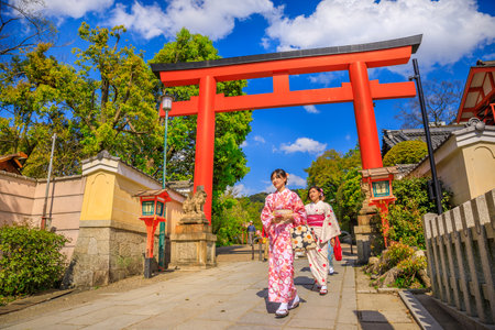 Kyoto, Japan - April 24, 2017: Japanese women in kimono cross one of red Torii Gate of Yasaka Shrine in spring season. Gion Shrine is one of most famous shrines between Gion and Higashiyama District.のeditorial素材