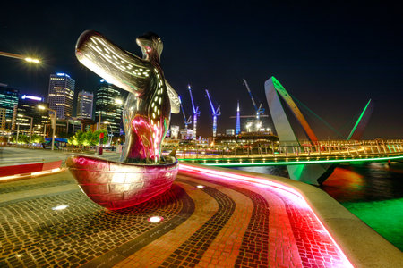 Perth, Australia - Jan 5, 2018: First Contact Sculpture on foreground at Elizabeth Quay Marina illuminated at night. Construction cranes and arcade of the Elizabeth Quay Bridge on the background.のeditorial素材