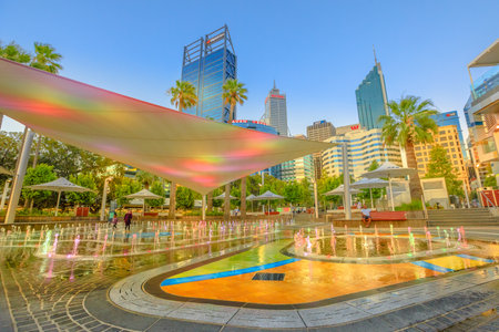 Perth, Australia - Jan 6, 2018: amusing water jets, misting, lighting of a new attraction for kids of BHP Billiton Water Park in Elizabeth Quay. Central business district on background at sunset.のeditorial素材