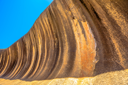 Golden colors of Wave Rock a rock formation that is shaped like a tall ocean wave, Hyden, Western Australia. Wave Rock is part of Hyden Rock in Hyden Wildlife Park. Blue sky. Perspective view.の写真素材