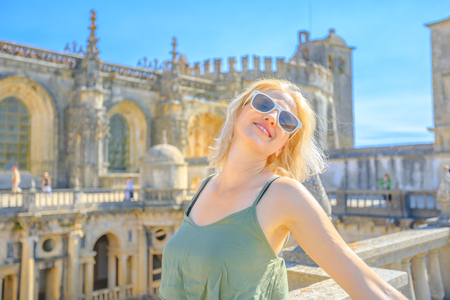 Tourism in Portugal. Carefree lifestyle woman at atop of Convent of Christ. Female tourist enjoying in Tomar, city of Knights Templar in Portugal, Europe. Summer holidays. Aerial view of Monastery.の写真素材