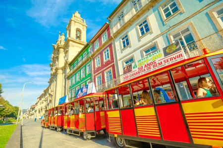 Braga, Portugal - August 12, 2017: red tourist train along Avenida Central alongside Convent of Congregados or Convent of Congregation in urban center of Braga, one of the oldest cities of Portugalのeditorial素材